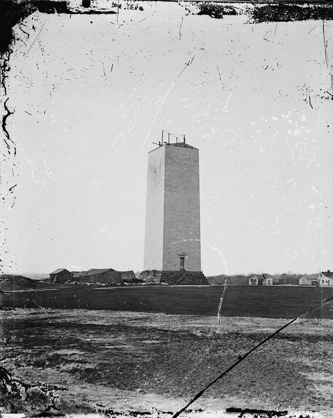 Black and white photo of unfinished Washington Monument about 150 feet high