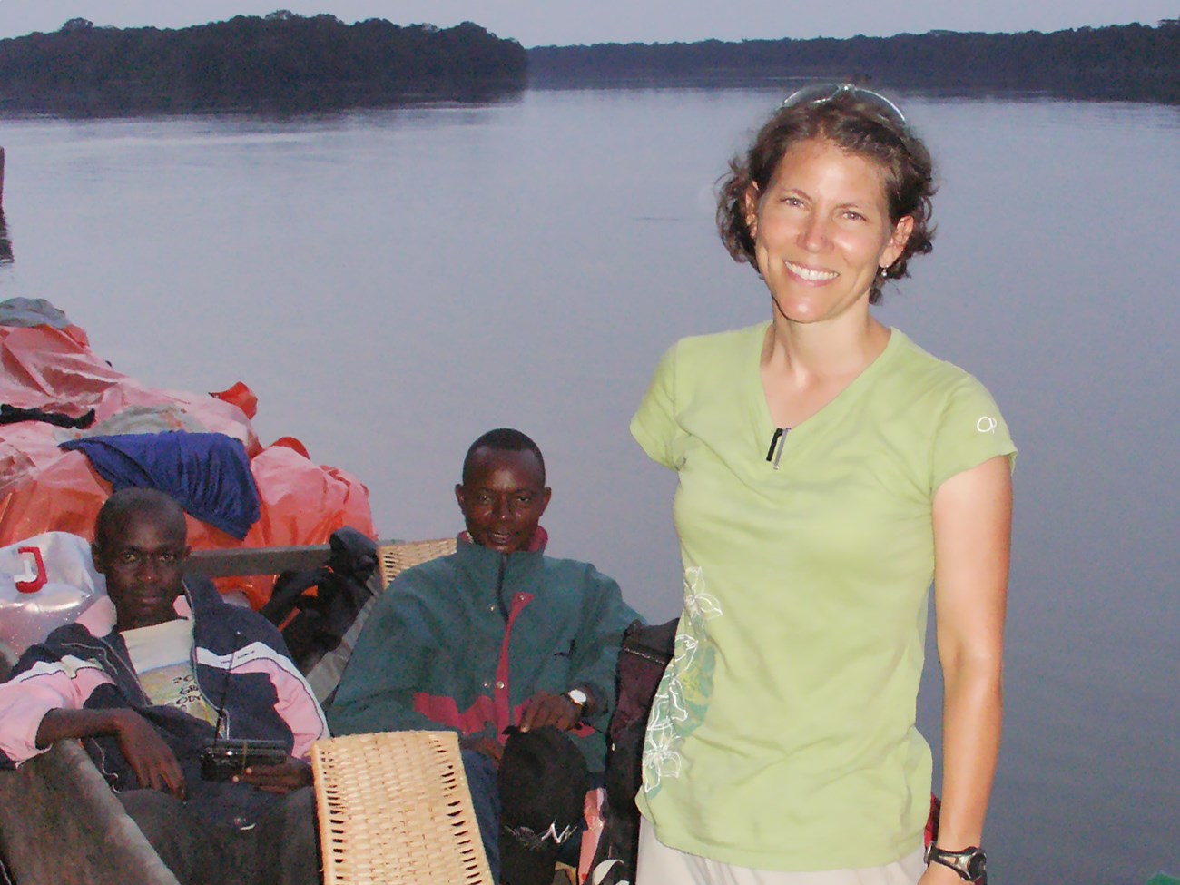 Jena standing up in a dugout canoe with some of her team members and their equipment.