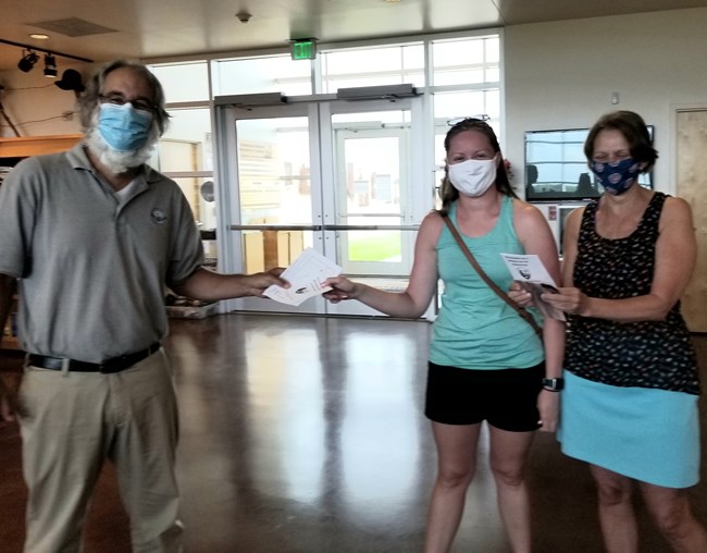 An employee presents the map and booklet to two individuals.