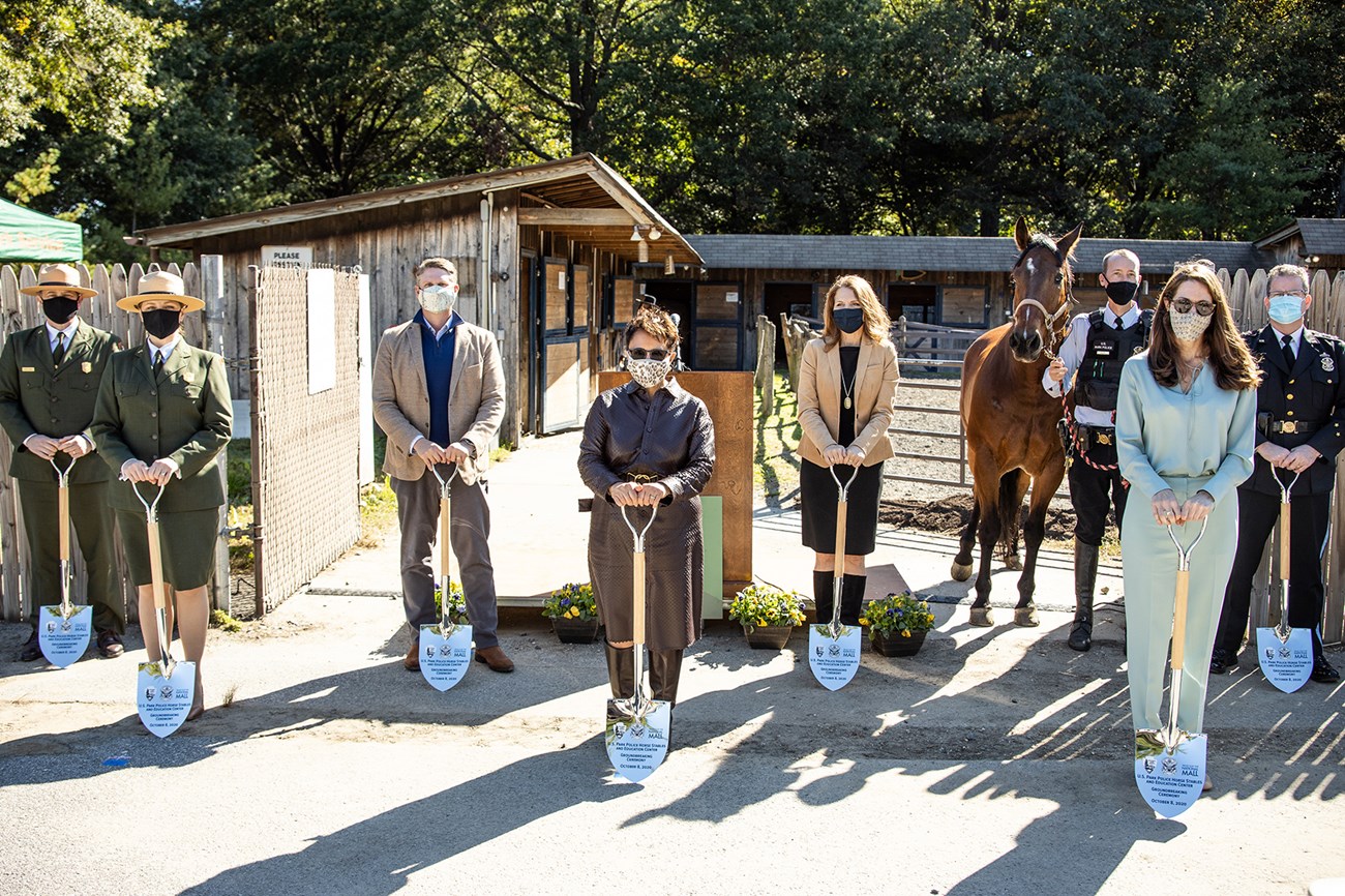 Women and men pose with shovels.