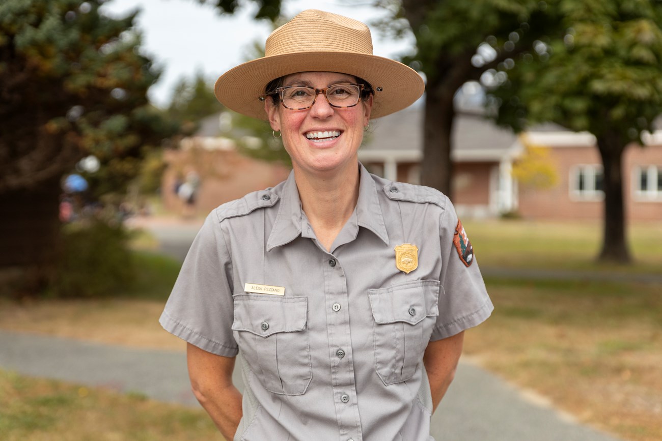 A park ranger smiles in front of an education campus