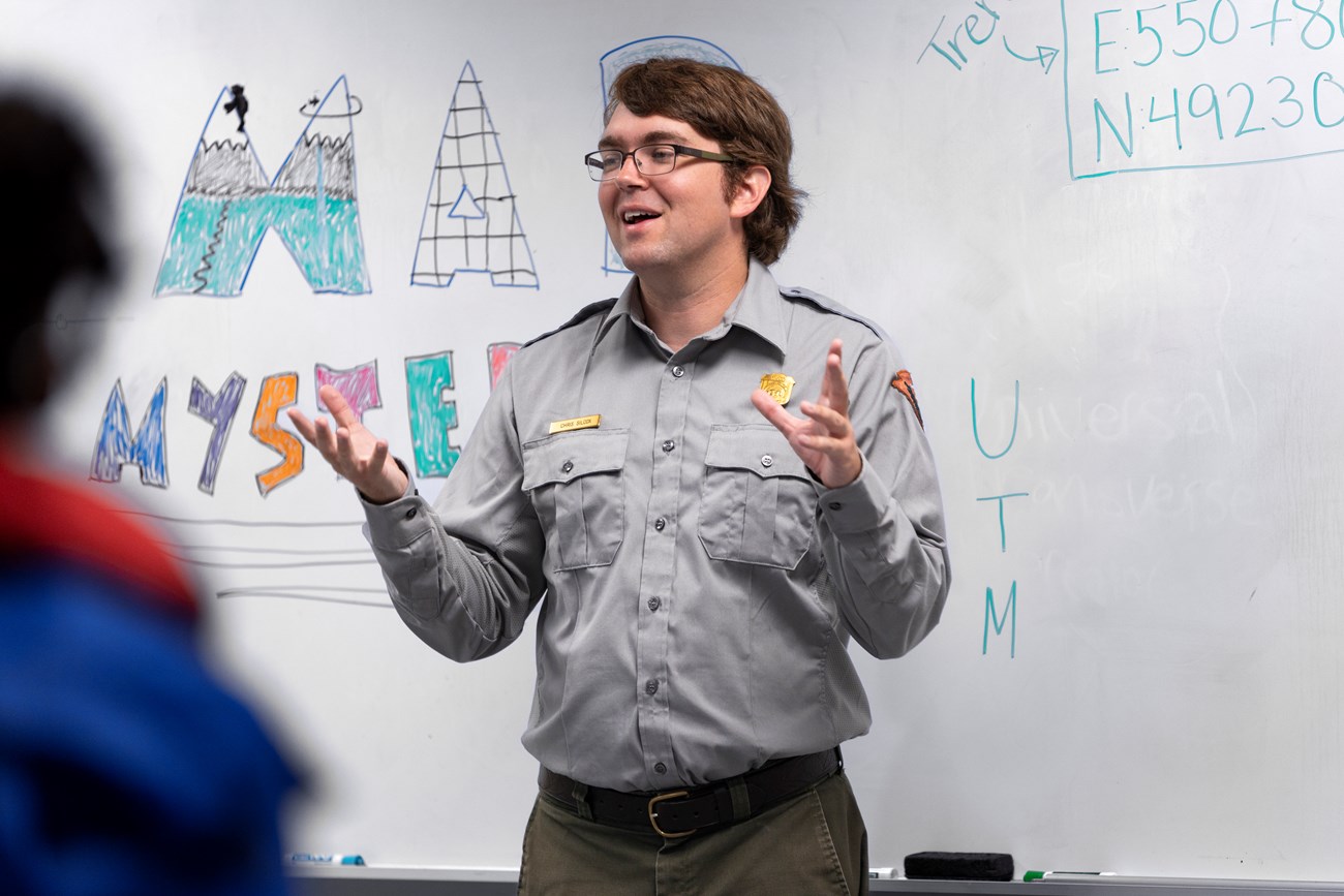 Ranger talks to school group in front of a white board.