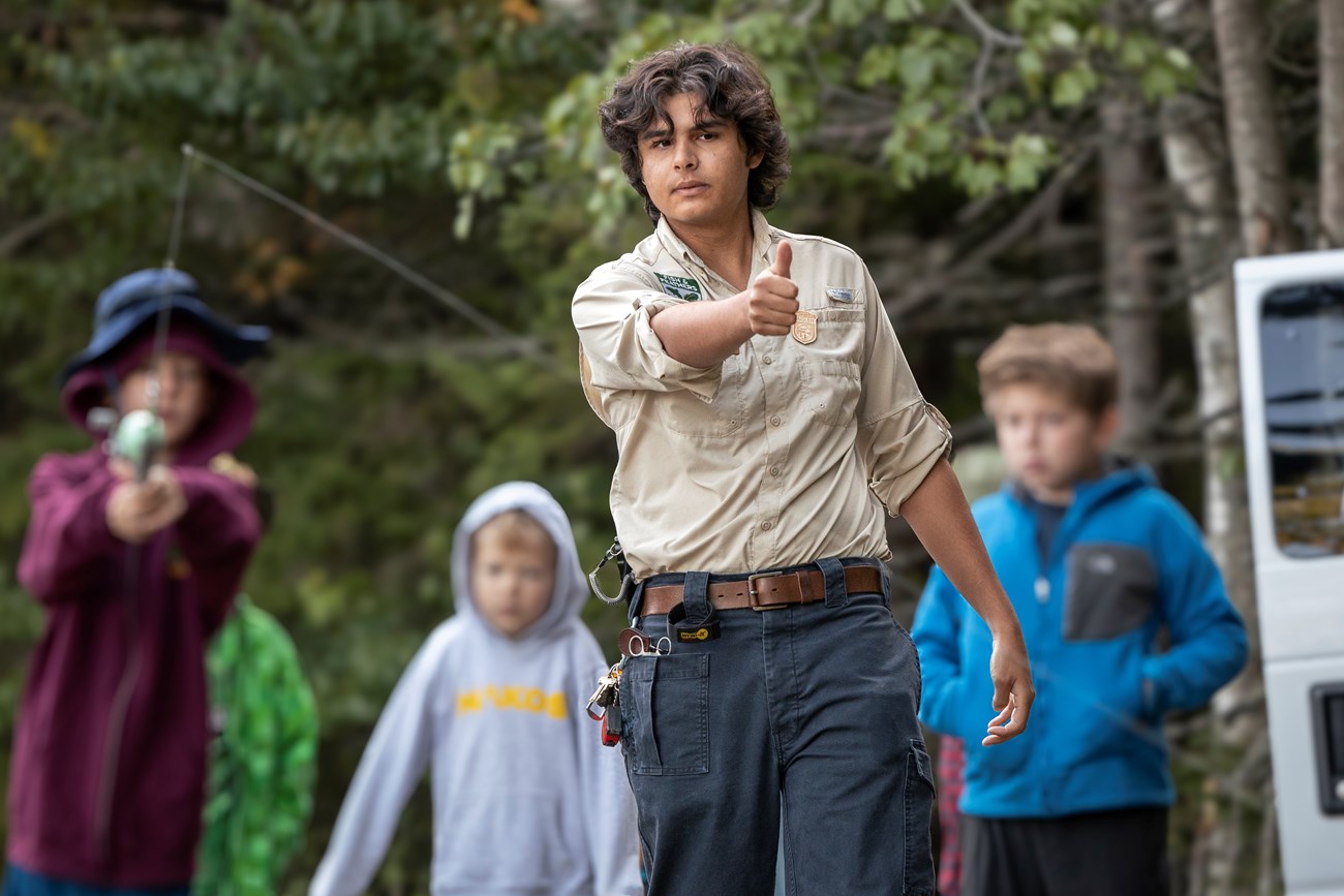 Intern teaching childrens how to cast a fishing rod.