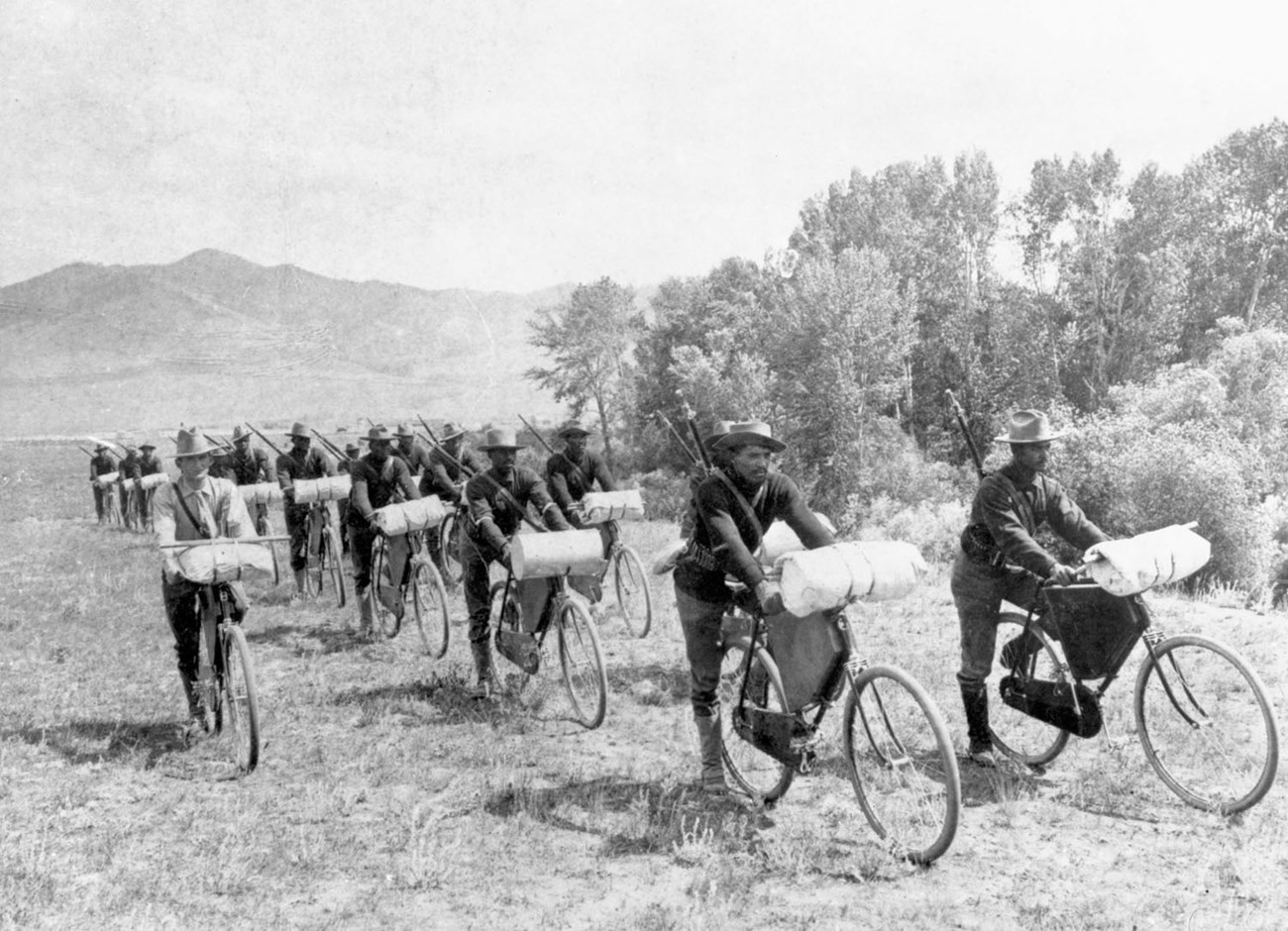 Group of male soldiers riding bicycles in a mountain area