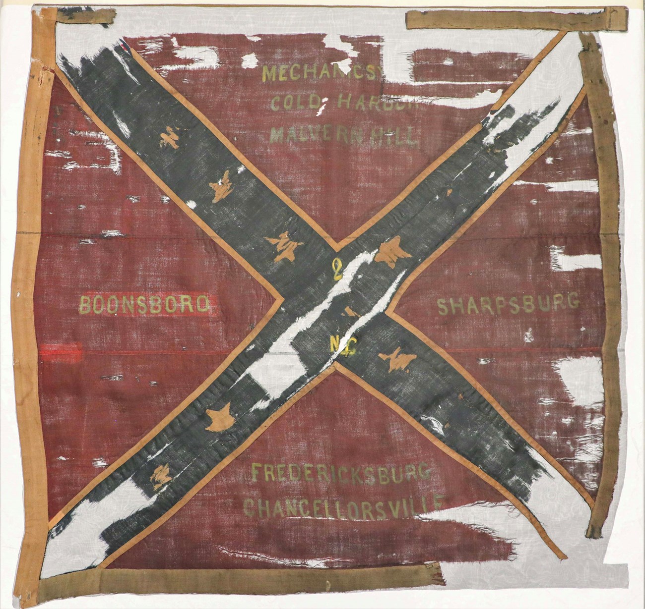 A red square flag with a Blue X on it, with gold stars in the X and the words "Boonsboro", "Mechanics, Cold Harbor, Malvern Hill", "Sharpsburg", and "Fredericksburg, Chancellorsville" on it.