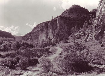 A dirt road winds through the mountain and the brush.