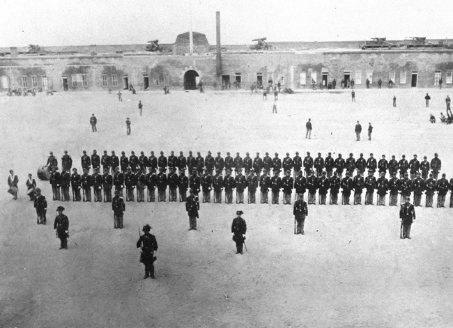 Black and white image of two rows of soldiers in the middle of a fort.