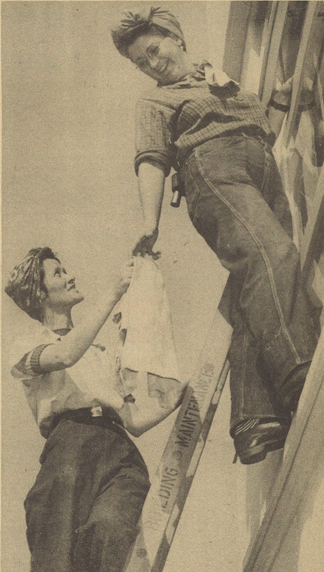 Two women clean windows together at the Oregon Shipyard Corporation office building.