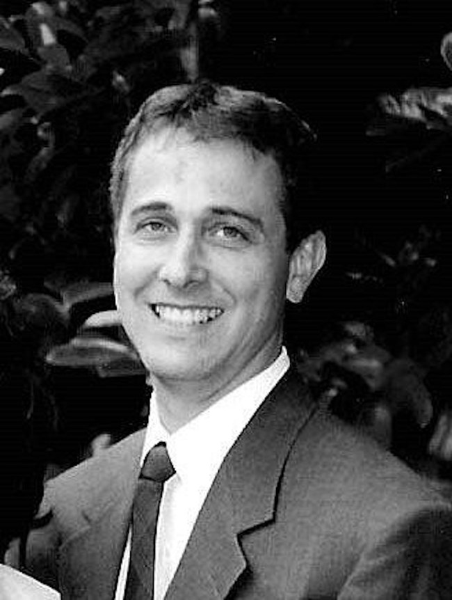 A black and white headshot photo of Patrick Sparks in a suit.
