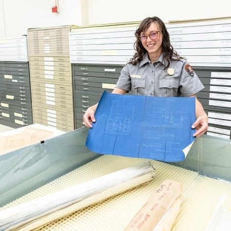 a park ranger holding up a large historic map