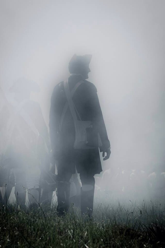 A Continental Army soldier stands among comrades in a thick fog of smoke.