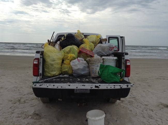 A pickup truck loaded with bags of trash.