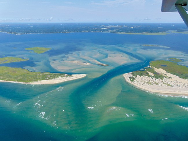 Aerial view of a barrier island cut in two by the sea.