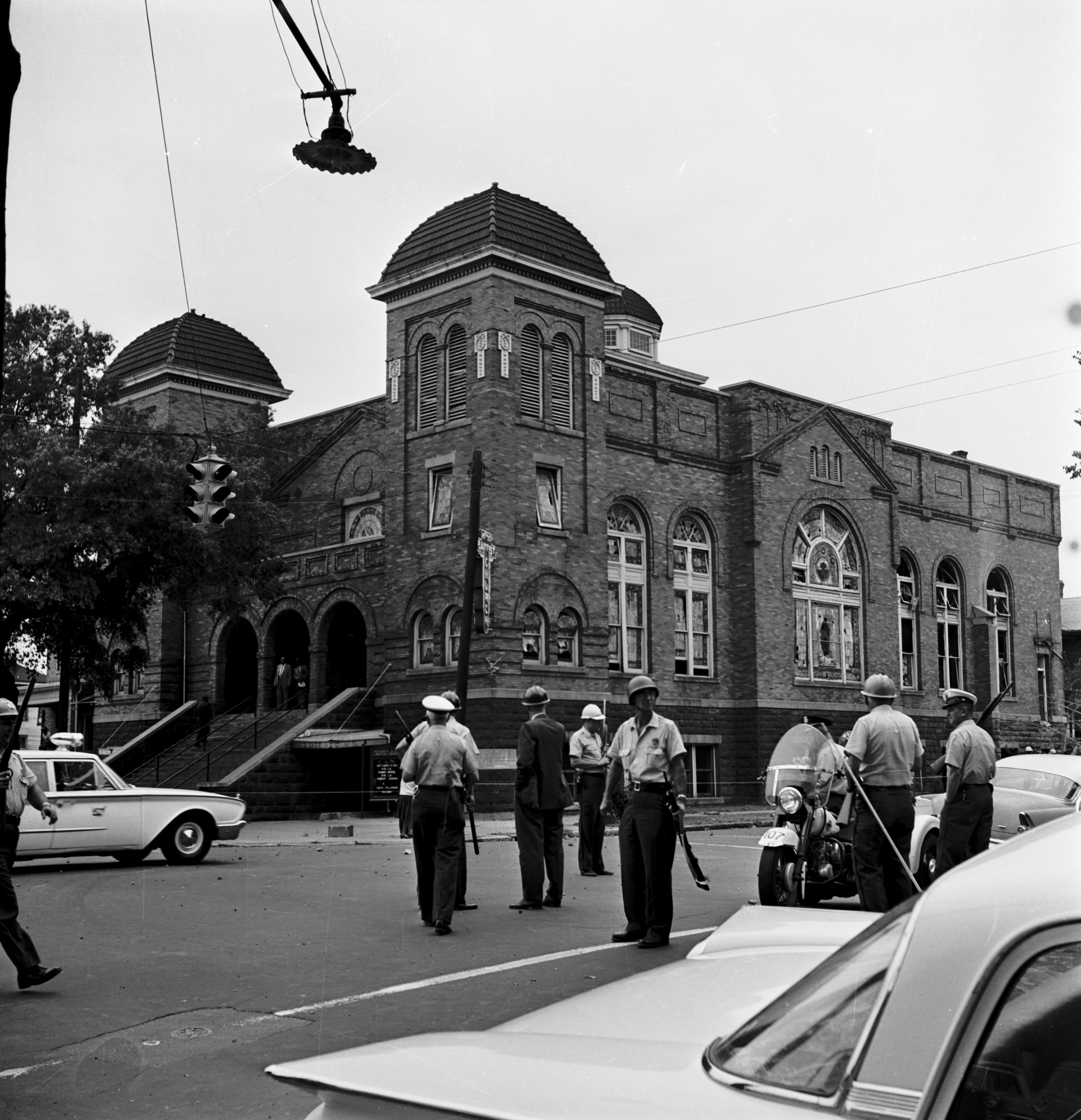 Police officers on guard outside 16th Street Baptist Church. Debris is scattered in the streets.