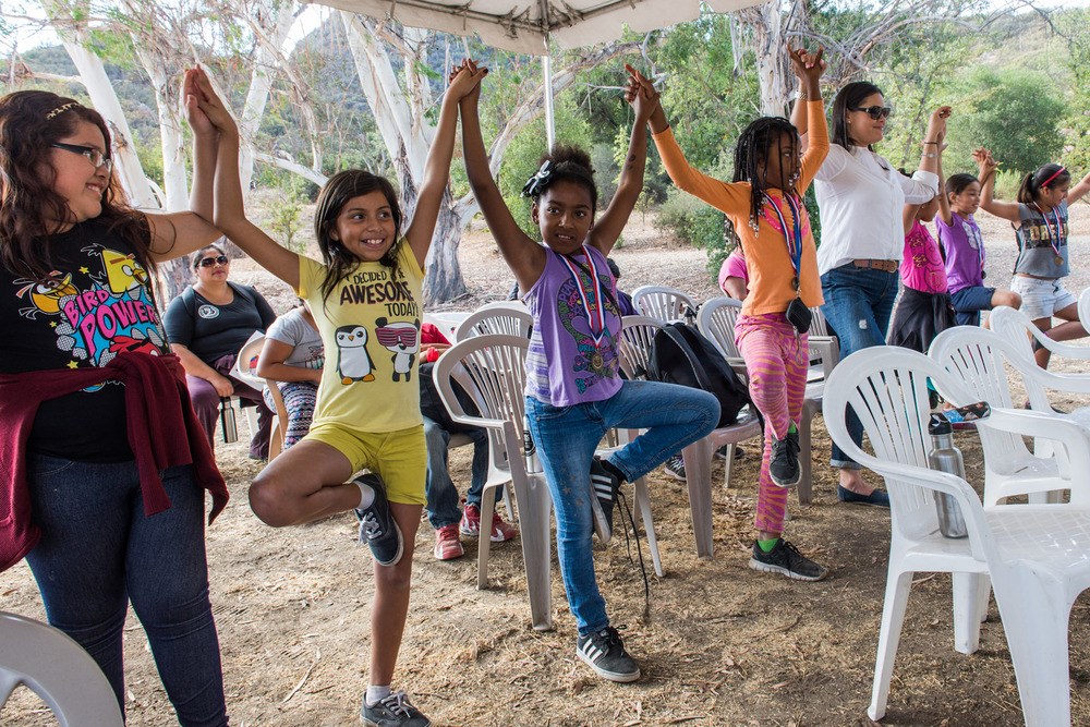 Group of mostly kids in a line doing yoga poses