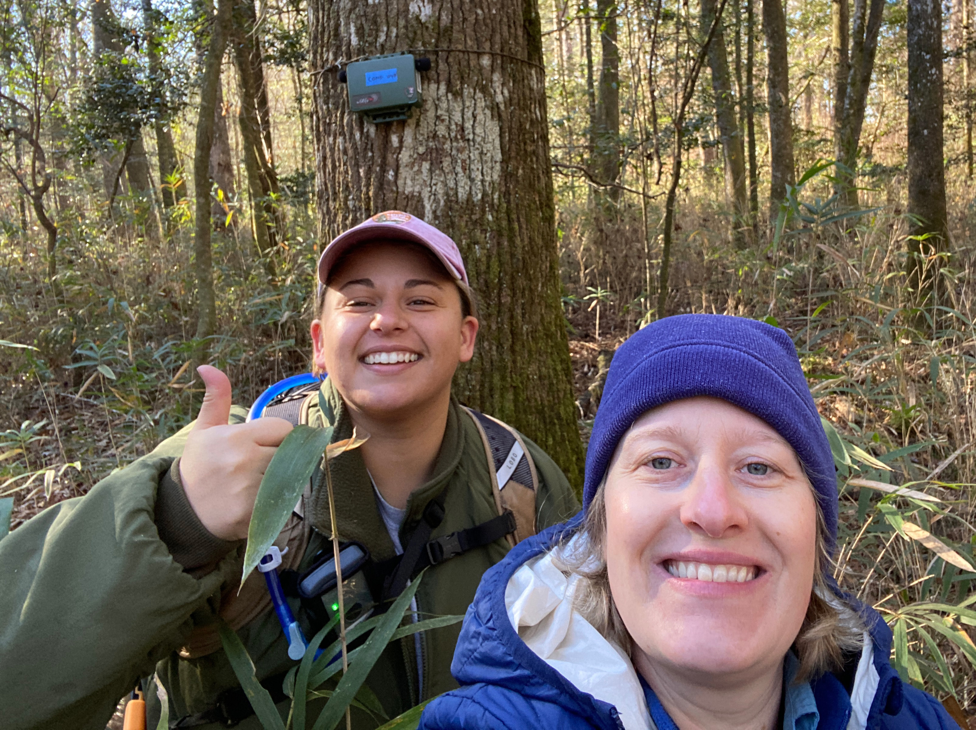 Two people smiling for a selfie in the woods