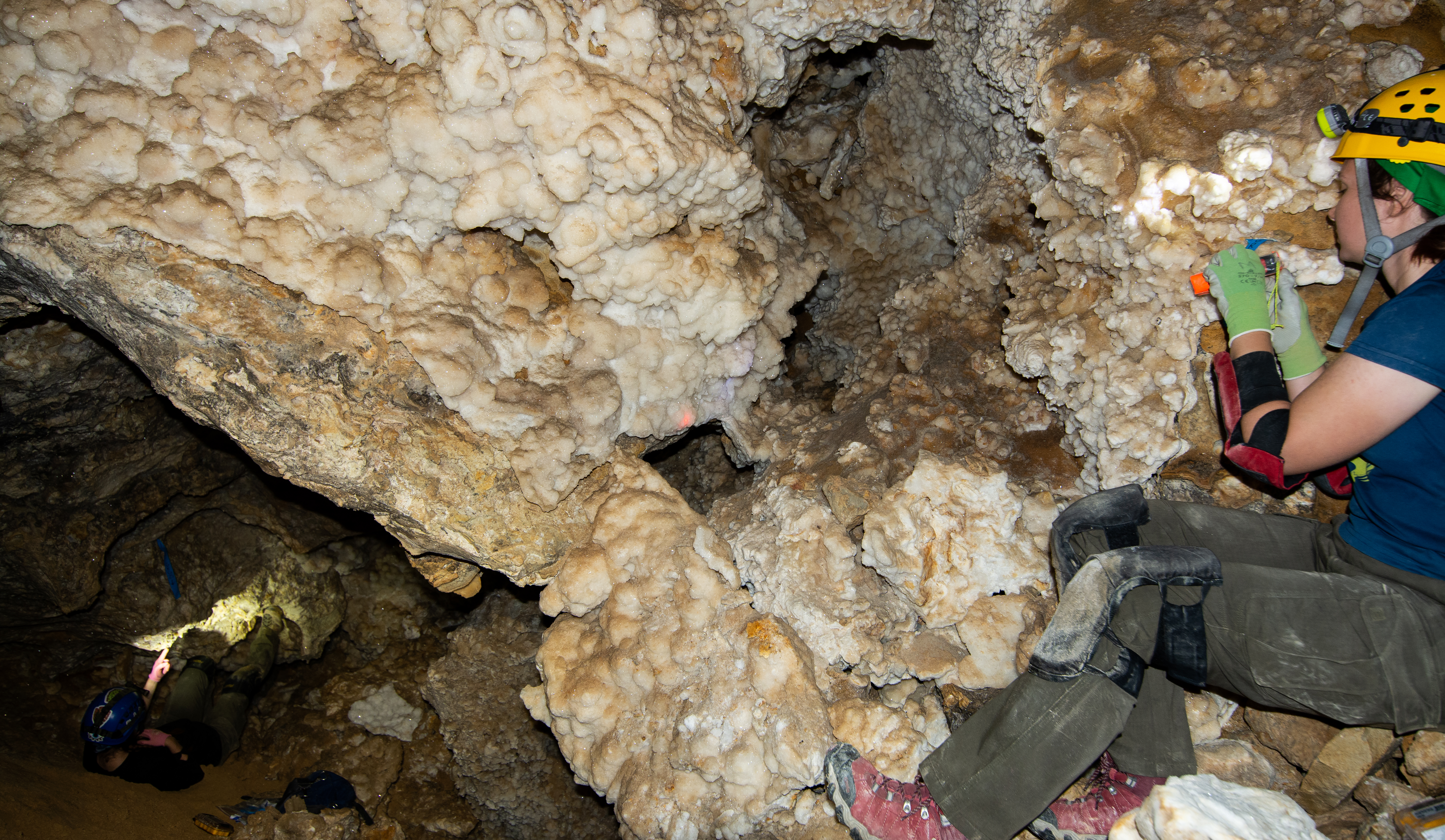 two people survey inside a cave passage