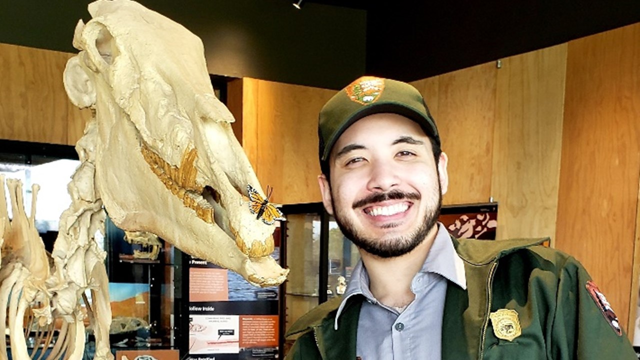 Alexander Kim smiling next to a dinosaur model