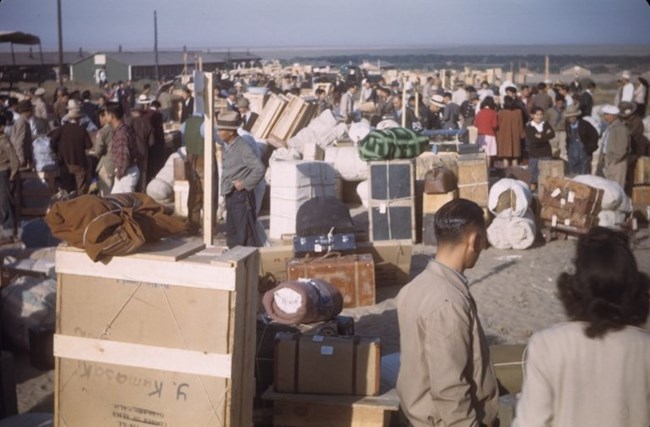Dozens of new Japanese Americans enter the Granada Relocation Center with wooden crates and luggage