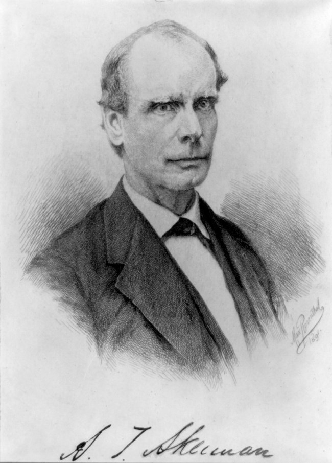 man wearing a black and white suit with bow tie. Autographed signature at bottom of image says "A. T. Akerman."