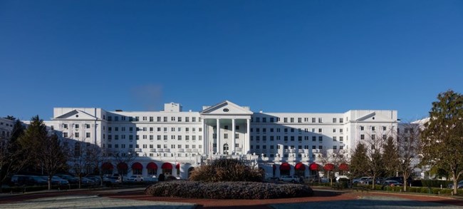 White hospital building, reminiscent of the White House. Central triangular portico atop Greek columns flanked by a multi-story wing on either side.