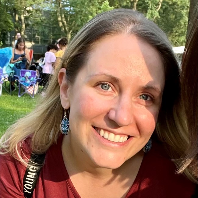 A close up of a woman with blonde hair and blue eyes smiling outdoors