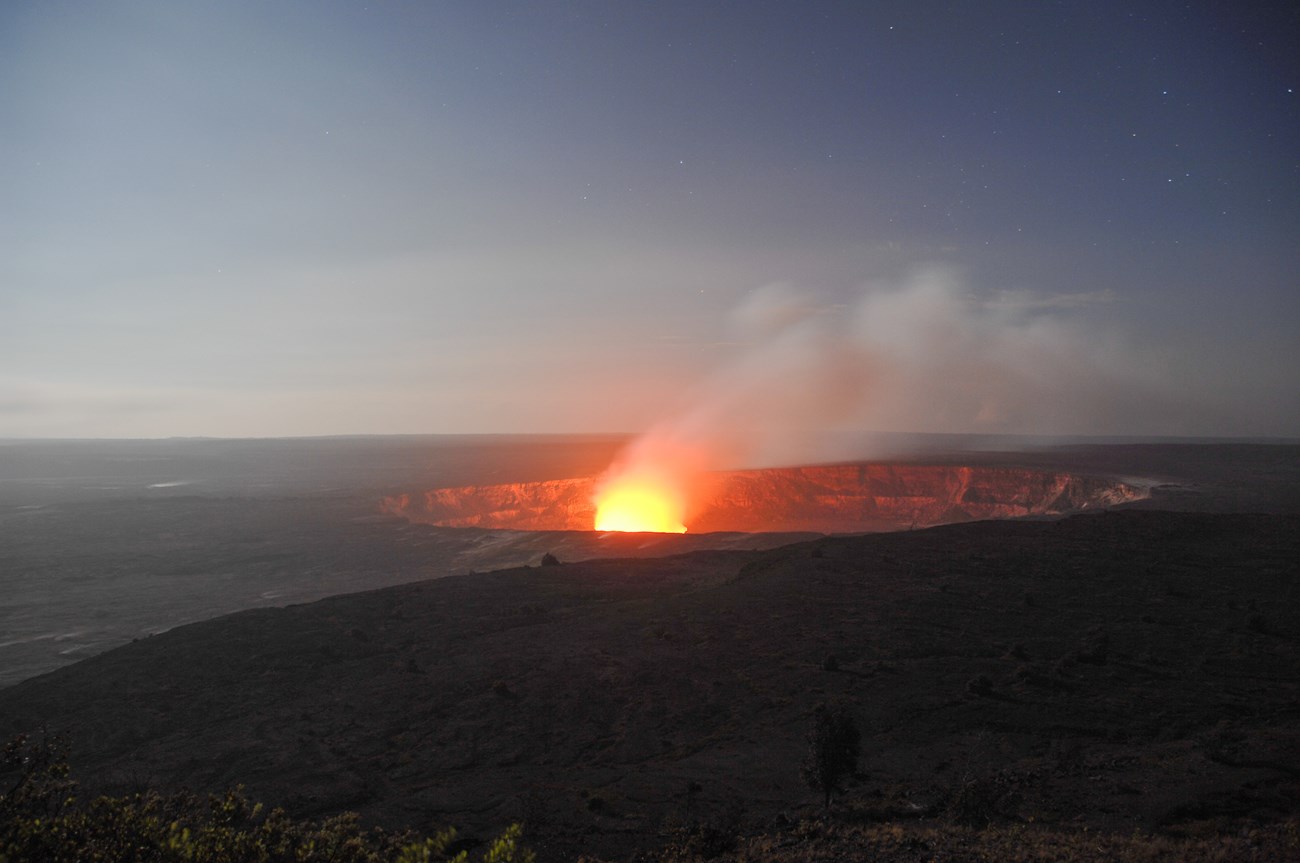 photo of glowing lava eruption in a large volcanic crater