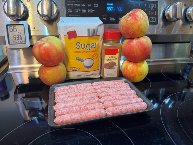 Breakfast sausage, apples, cinnamon and sugar on a stove.
