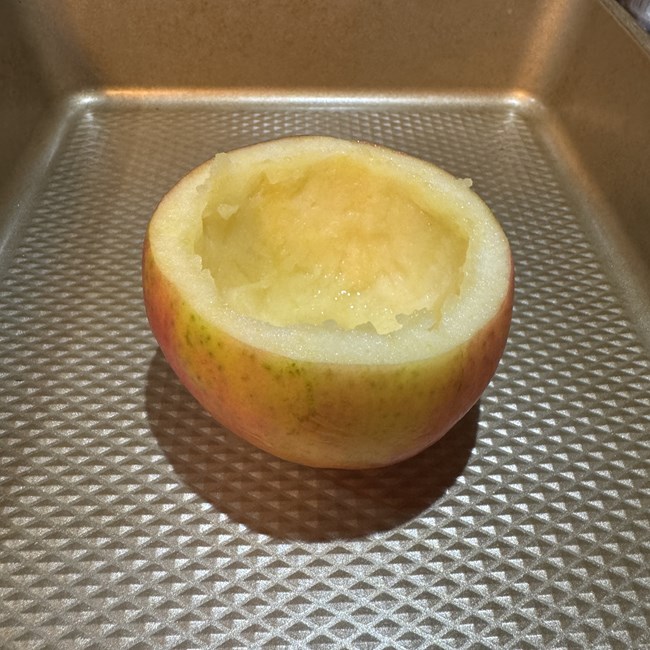 An apple with the top sliced off horizontally and the inner flesh cored out.