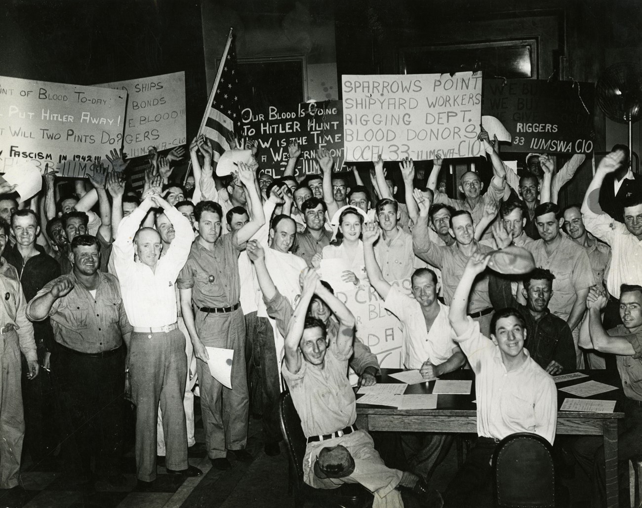 Black and white photo of large group of men gathered in a room celebrating giving blood during WW2