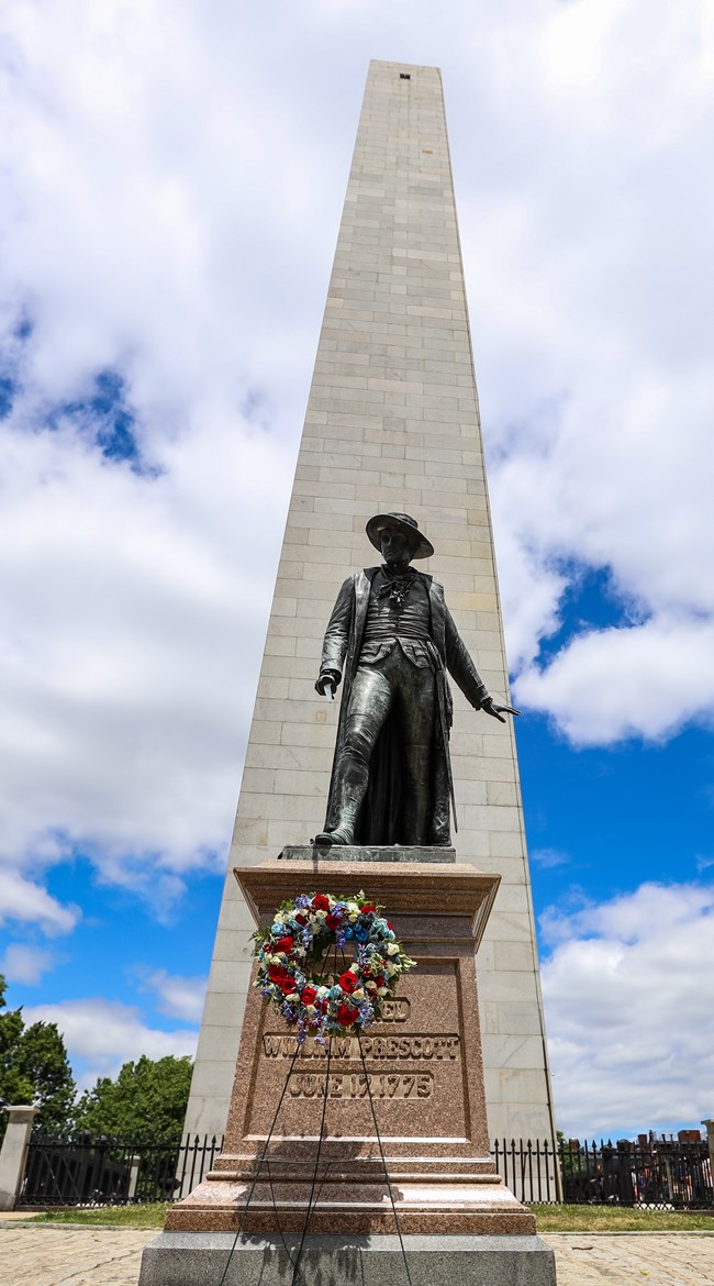 A stone monument behind a statue of a person.