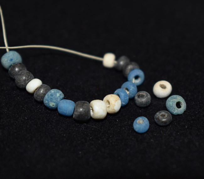 Close-up of a necklace with alternating blue and white beads resting on a black background