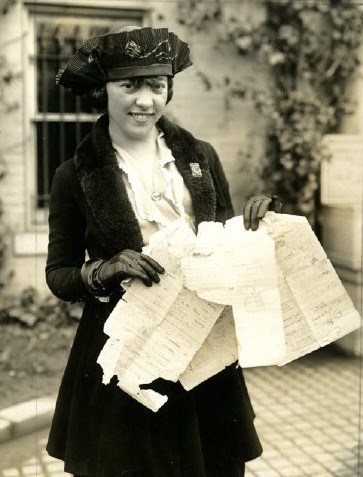 Suffragist holding the tattered sheets of the suffragists' lobby list