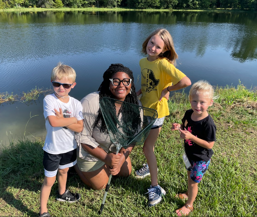 An adult with students near a body of water