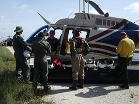 Several people stand around a helicopter