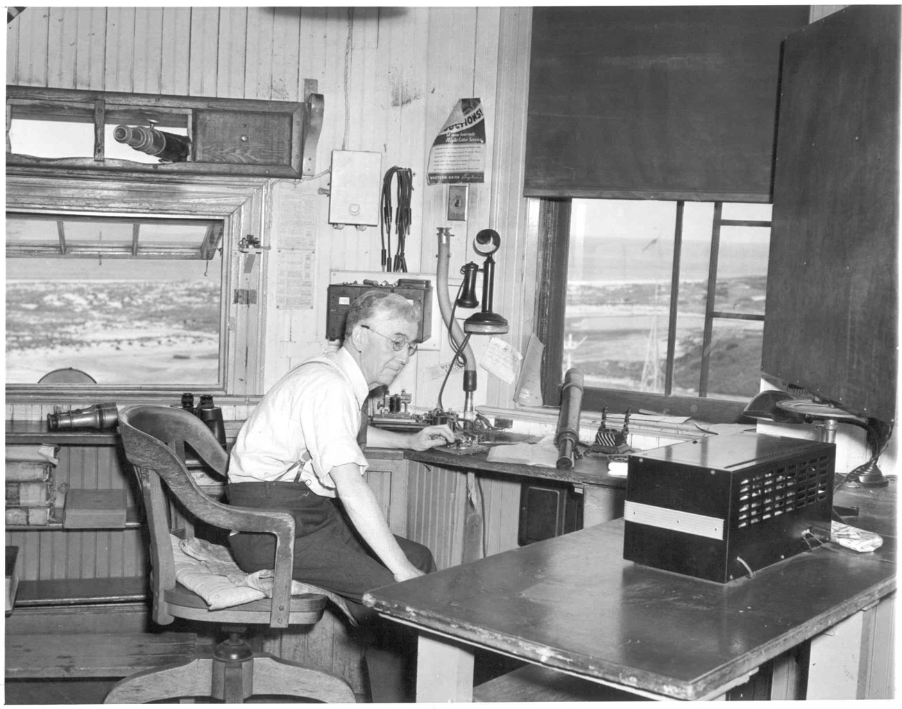 a man sits at a desk with his hand on a morse code device