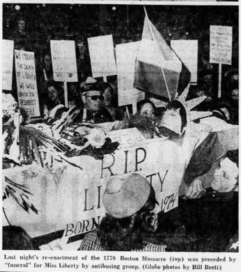 Black and white photo of a women dressed as the statue of liberty laying in a coffin labeled R.I.P. Liberty