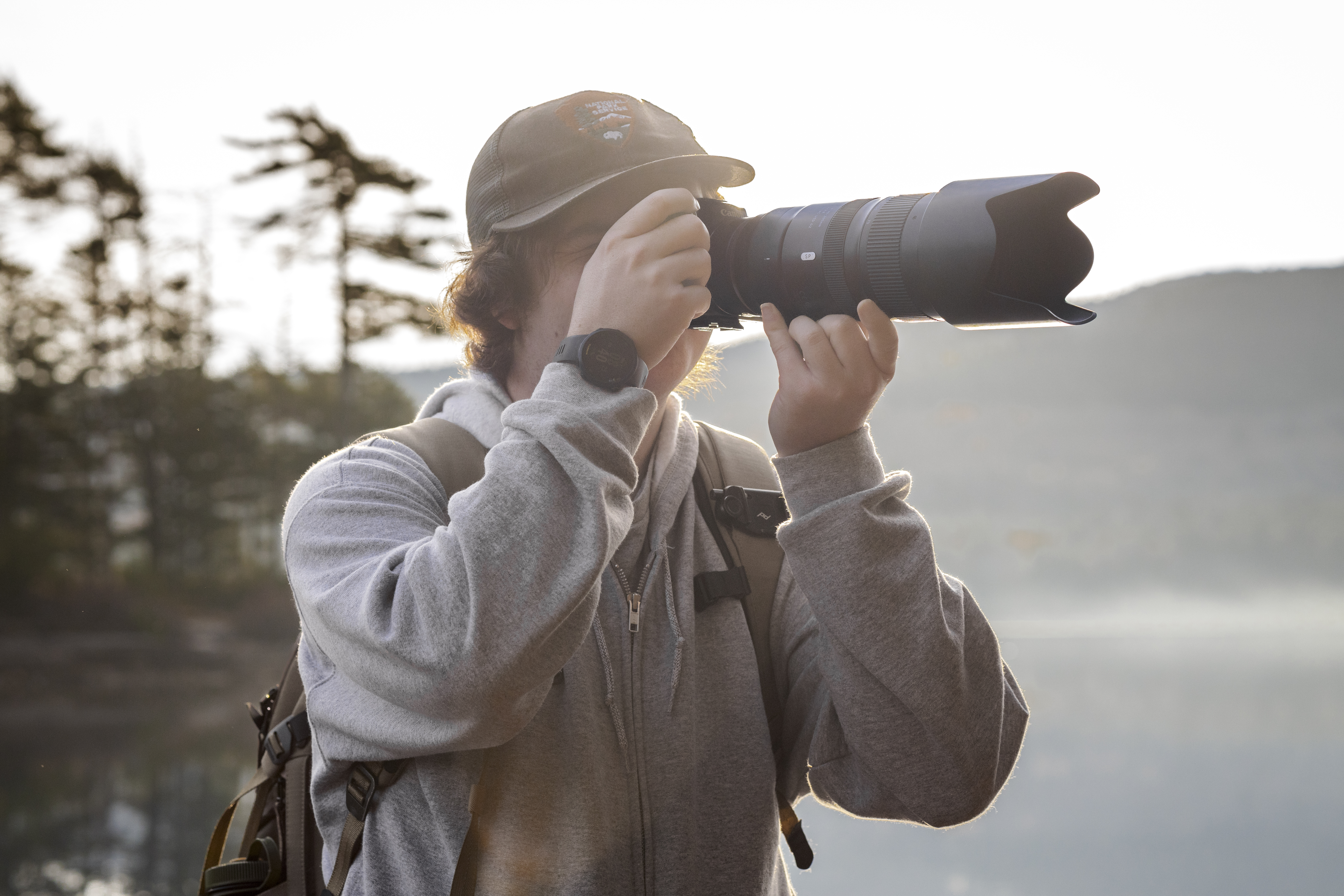 Brady taking a photo with a telephoto lens in the park.