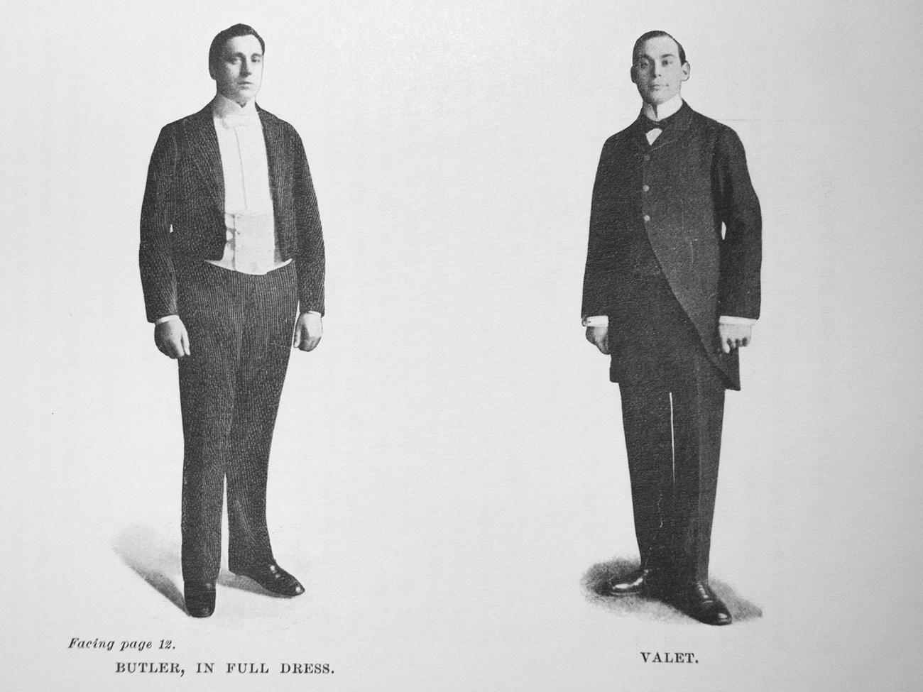 A photograph of two men, a butler and a valet, in formal suits.