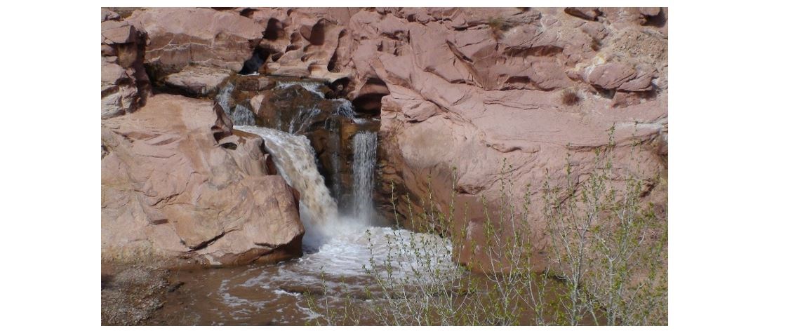 Photo shows a substantial drop in the river with two side-by-side waterfalls and a pool below. The entire setting is rocky.