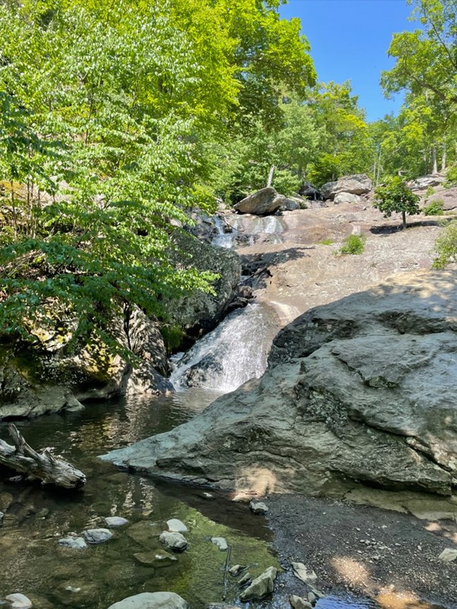 An image of a waterfall going down large rocks with trees around it.