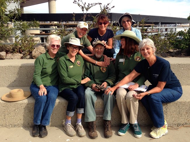 A group of volunteers sit on steps and pose for a picture