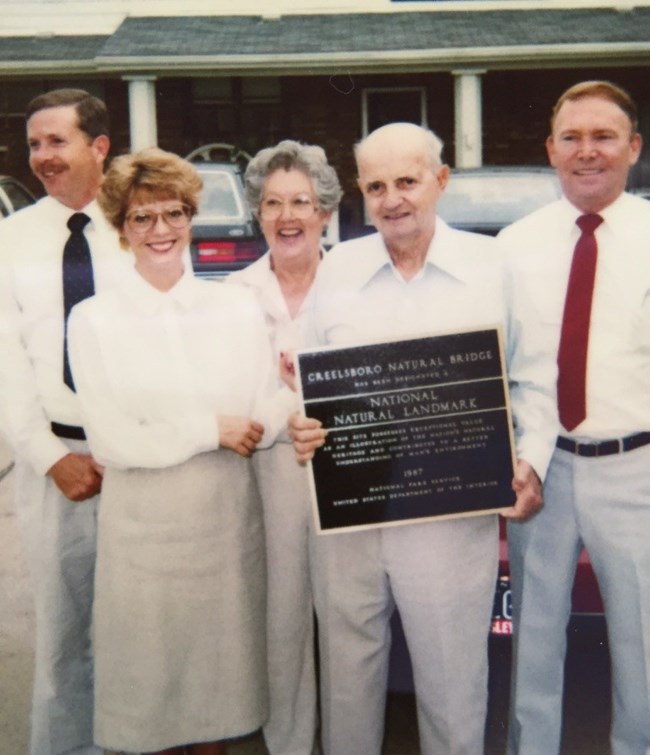 Five people standing with plaque