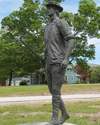 A statue of a young person in colonial attire carrying a musket and in mid-stride.