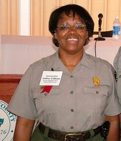 Color photo of Audrey Calhoun from the waist up. She is posing in her NPS uniform with a white name tag with red ribbon pinned to it.