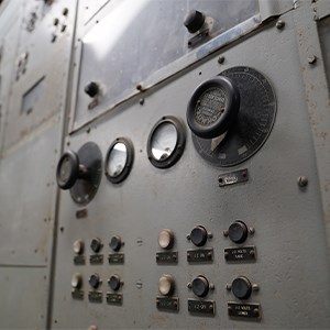 Several rusted and dusty dials and gauges along a cubicle wall.