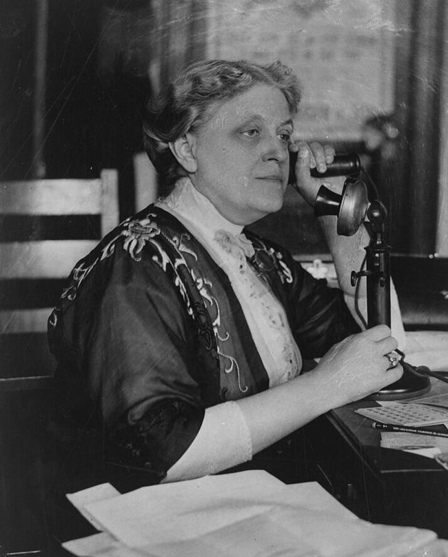 Black and white photo of Carrie Chapman Catt speaking on an old fashioned candlestick phone. LOC