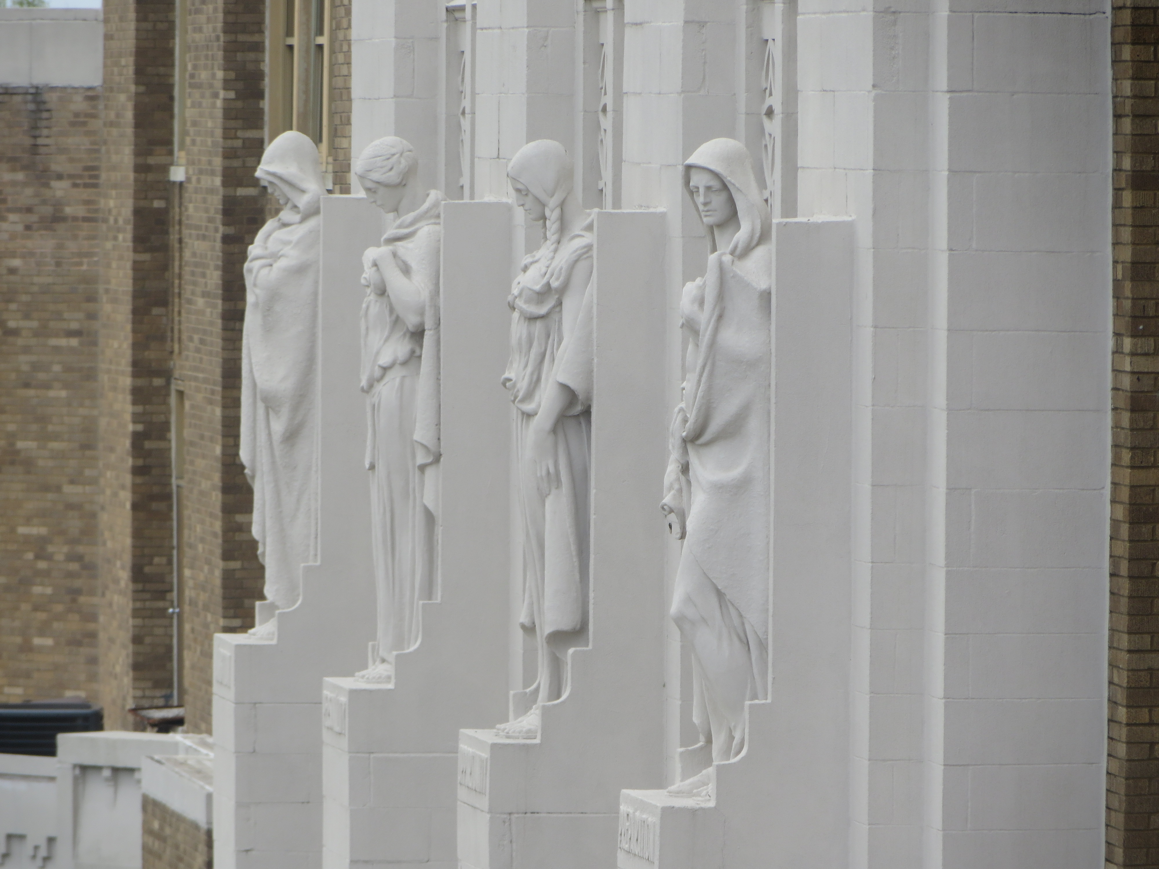 Four stone figures stand watch over the school's main entrance and represent ambition, personality, opportunity and preparation.