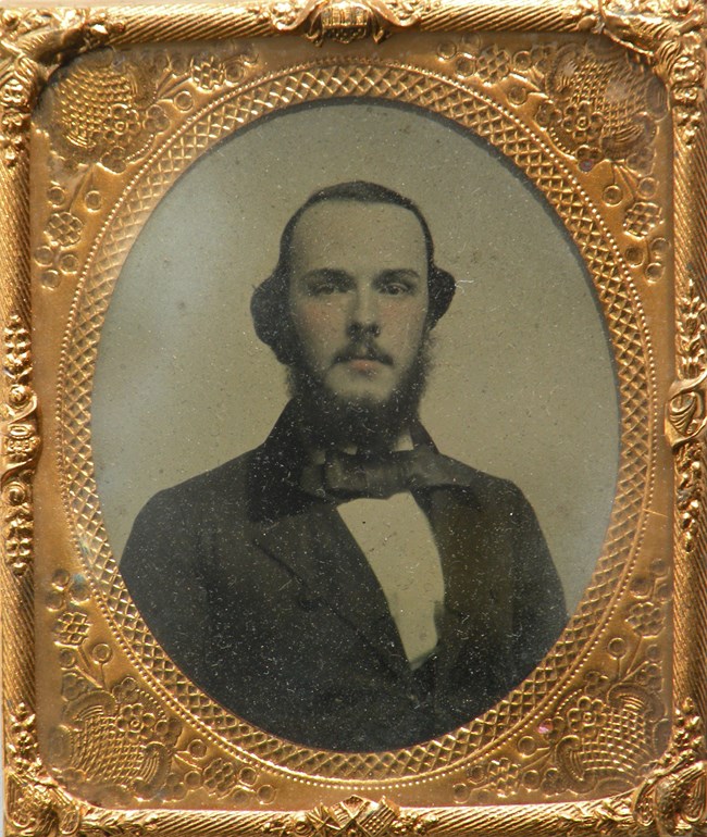 A golden frame with a black and white image of a man in a suit.