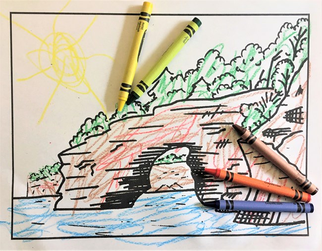 Colored in cliffs coloring page with crayons laying on the top of it.